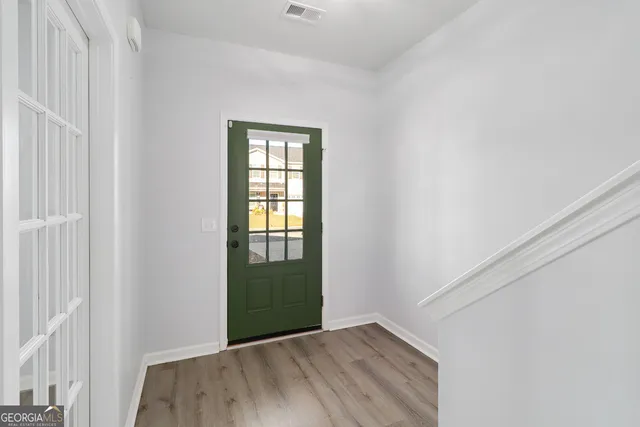 a view of an empty room with wooden floor and a window