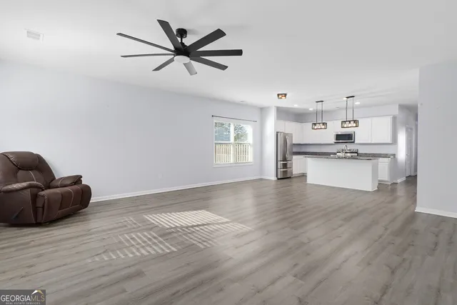 a living room with stainless steel appliances furniture and a wooden floor
