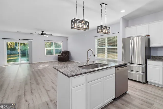 a kitchen with stainless steel appliances granite countertop a sink a refrigerator a stove and a wooden floors