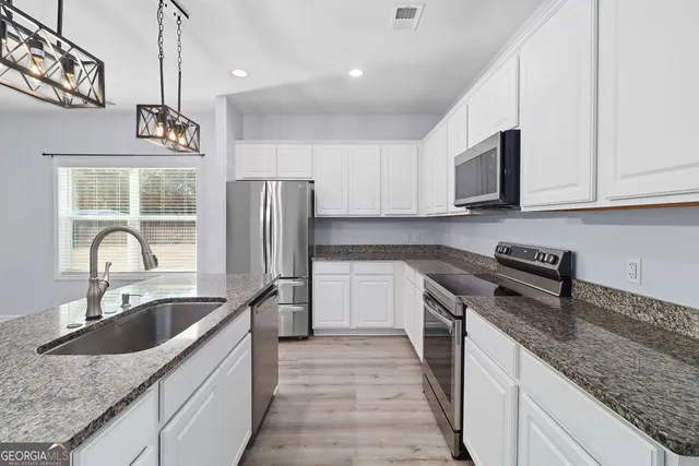 a kitchen with stainless steel appliances granite countertop a sink stove and refrigerator
