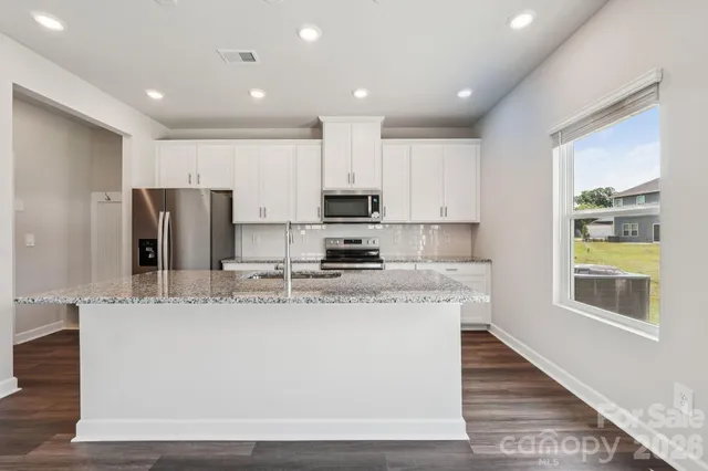 a large kitchen with stainless steel appliances granite countertop a stove a sink and a refrigerator