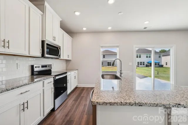 a kitchen with stainless steel appliances granite countertop a stove a sink and a microwave