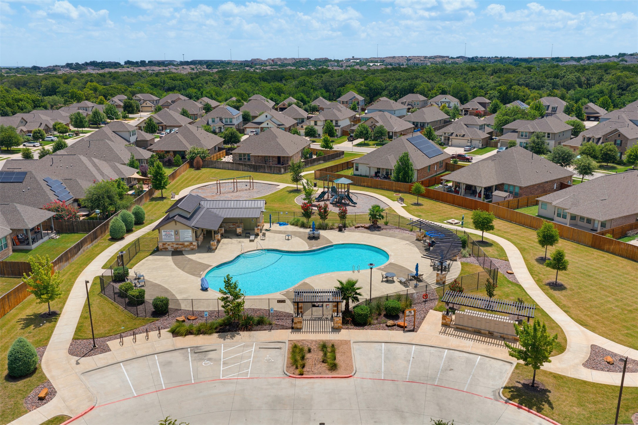 12613 Twisted Root Drive Manchaca, TX 78652 - Photo 33 of 33 An aerial perspective showcases a vibrant community pool area, complete with playful splash pads, a pavilion, and surrounding lush green spaces.