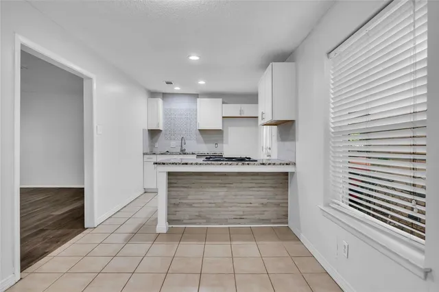 a large white kitchen with granite countertop a sink and a stove top oven