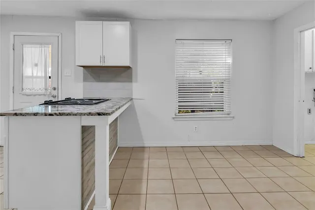 a view of kitchen with white cabinets and window