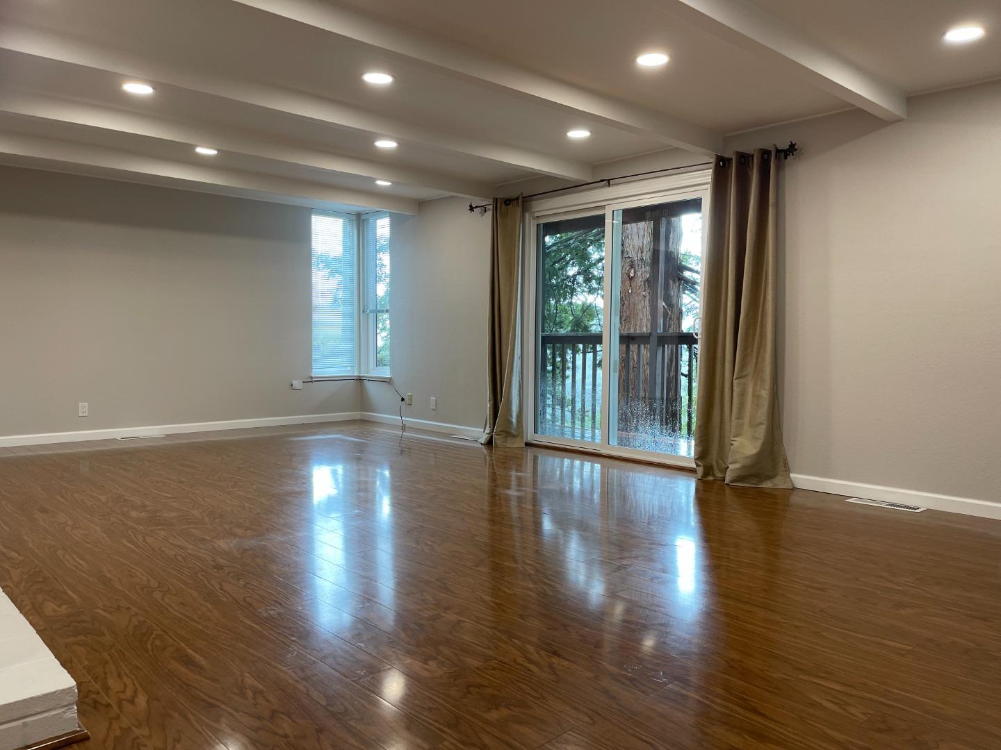 2625 Sequoia Way Belmont, CA 94002 - Photo 11 of 18 an empty room with wooden floor and windows with curtains