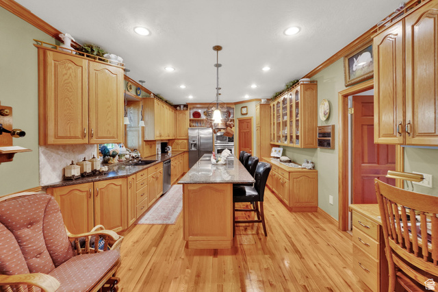 7740 Keswick Road Sandy, UT 84093 - Photo 20 of 74 Spacious kitchen featuring extensive wood cabinetry, granite countertops, wood-finish flooring, a central island with seating, and recessed lighting