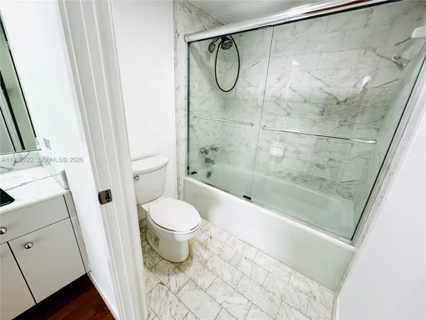 a bathroom with a granite countertop bathtub shower and toilet