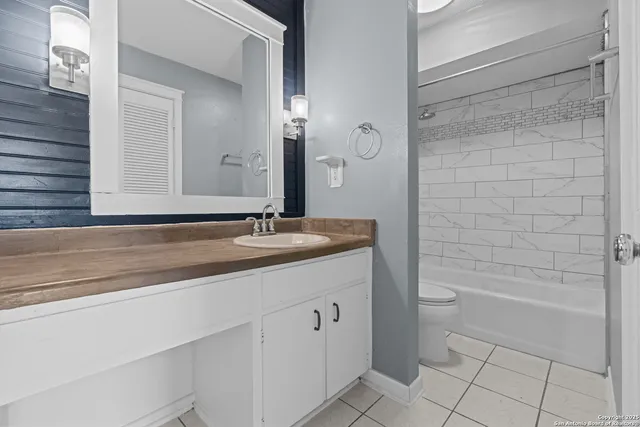 a bathroom with a granite countertop sink a toilet and shower