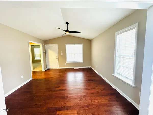 a view of an empty room with wooden floor and a window