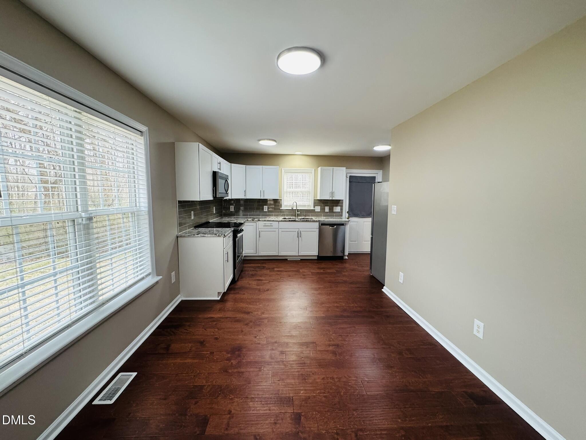6904 Fox Haven Place Raleigh, NC 27616 - Photo 5 of 17 a kitchen with stainless steel appliances granite countertop a stove top oven a sink dishwasher a refrigerator and white cabinets with wooden floor