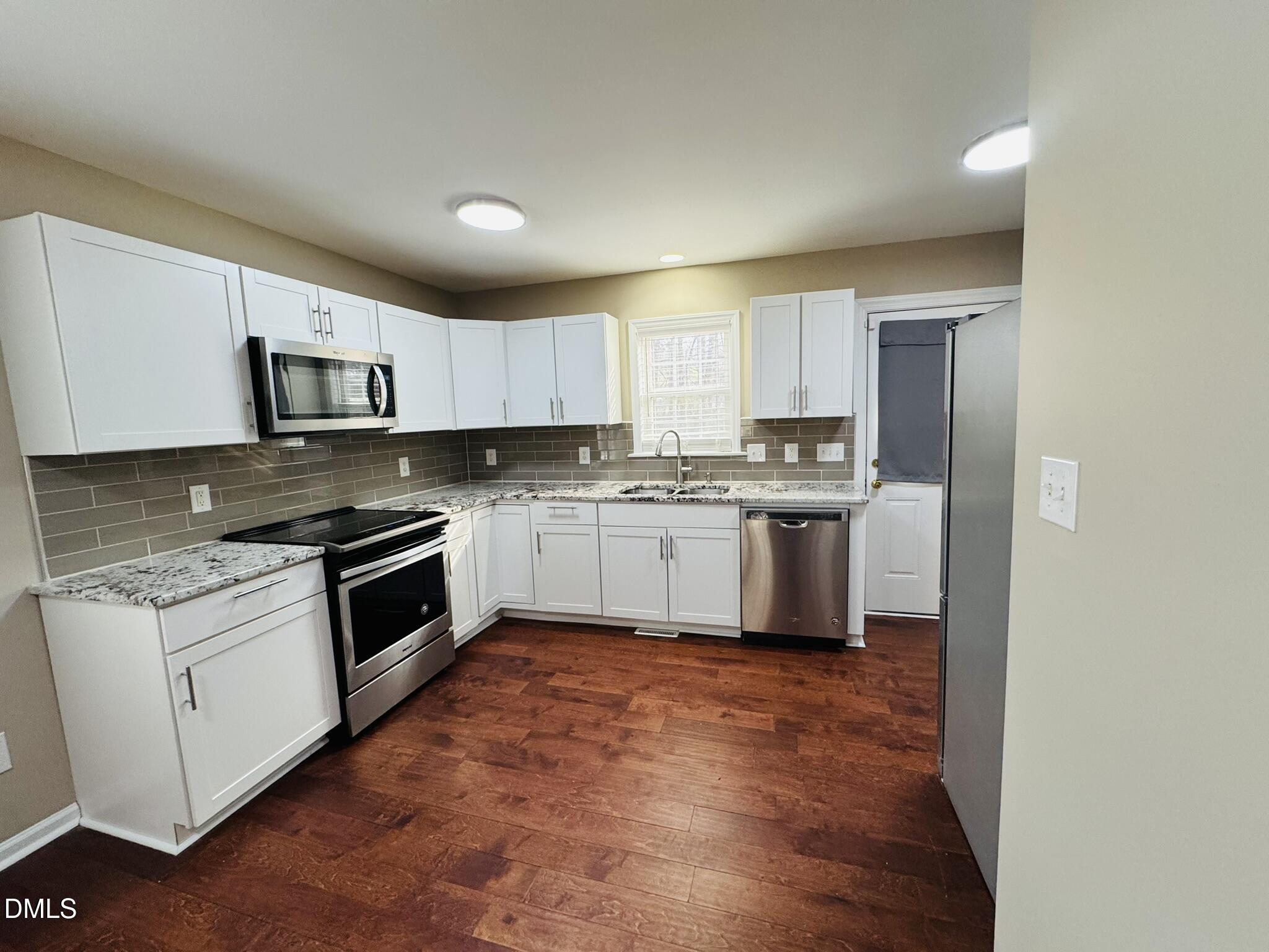 6904 Fox Haven Place Raleigh, NC 27616 - Photo 6 of 17 a kitchen with stainless steel appliances granite countertop a stove top oven a sink and dishwasher a refrigerator with wooden floor