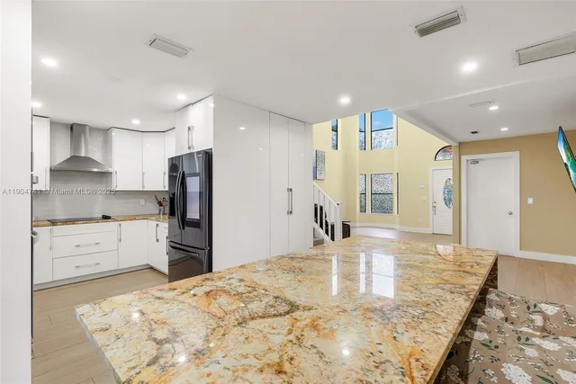 a kitchen with stainless steel appliances kitchen island granite countertop a refrigerator and a stove top oven