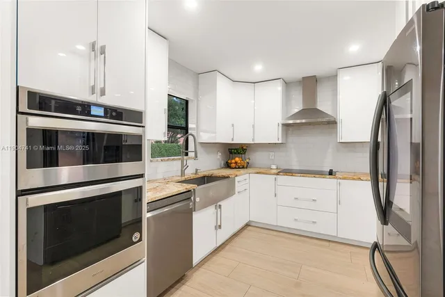 a kitchen with stainless steel appliances white cabinets and a stove top oven
