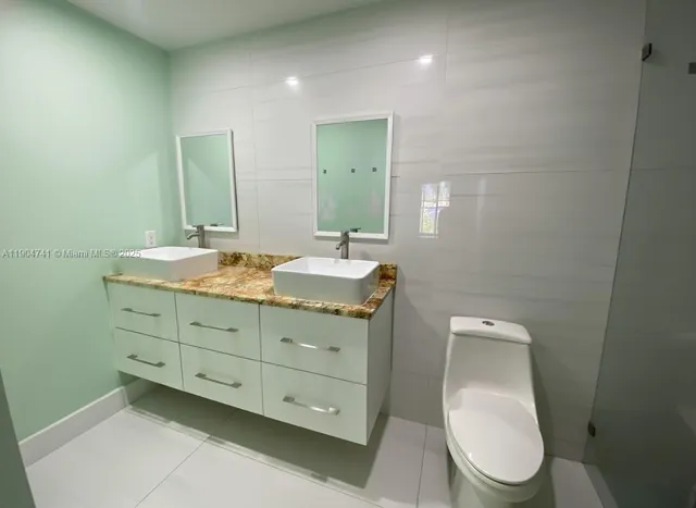 a bathroom with a granite countertop toilet sink and mirror