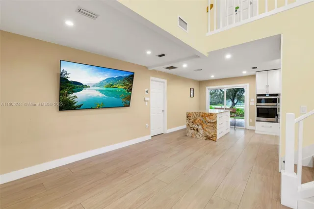 an empty room with wooden floor and a kitchen