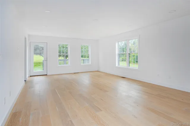 a view of an empty room and window and wooden floor