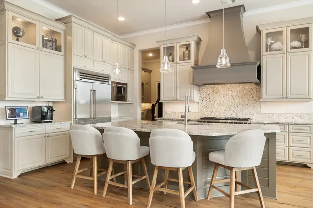 a kitchen with stainless steel appliances granite countertop a stove a sink dishwasher a stove and white cabinets with wooden floor