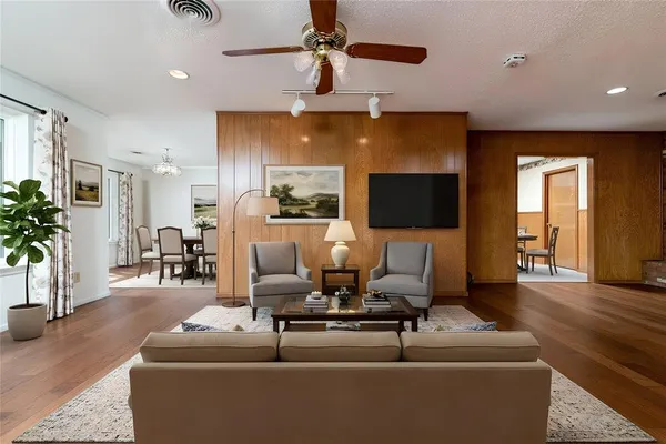 a view of an empty room with wooden floor and a ceiling fan