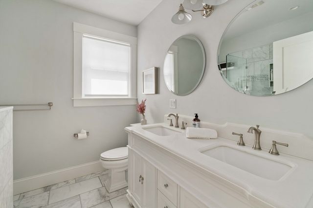 a bathroom with a granite countertop toilet sink and mirror