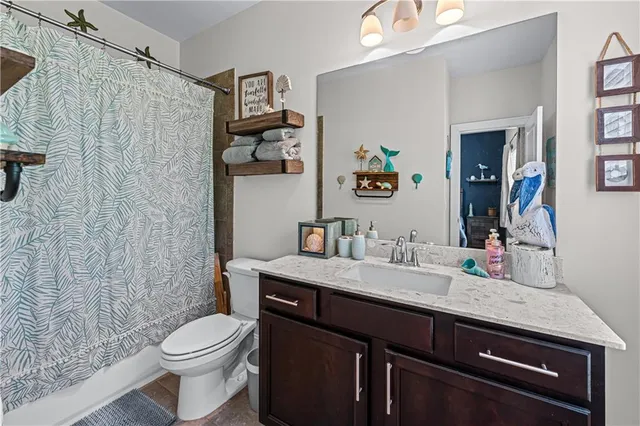 a bathroom with a granite countertop sink a toilet and a shower curtain