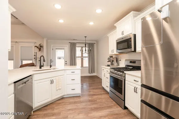 a kitchen with stainless steel appliances granite countertop white cabinets a sink a stove a refrigerator and a microwave