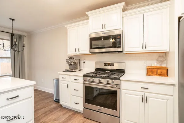 a kitchen with cabinets stainless steel appliances and wooden floor