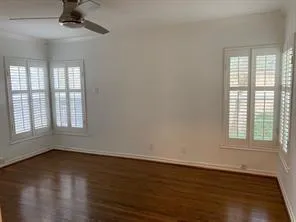 an empty room with wooden floor chandelier fan and windows