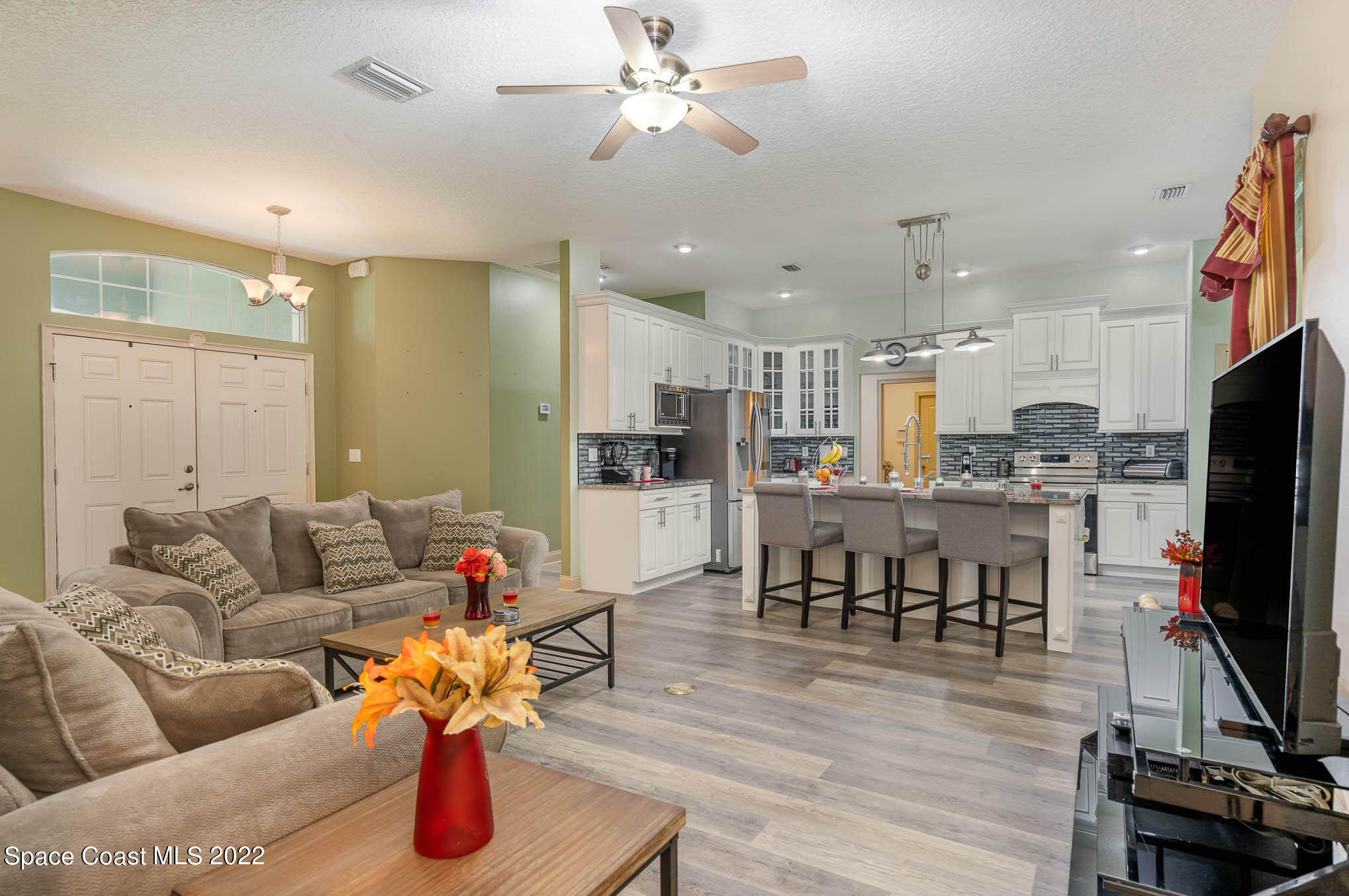 762 Seymour Road Northeast Palm Bay, FL 32905 - Photo 9 of 29 a living room with furniture kitchen view and a flat screen tv