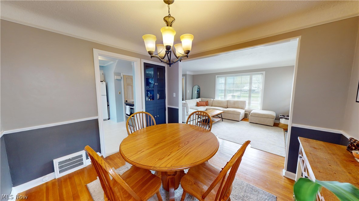 5175 Mayview Road Cleveland, OH 44124 - Photo 7 of 14 Dining space with hardwood / wood-style flooring, crown molding, and an inviting chandelier