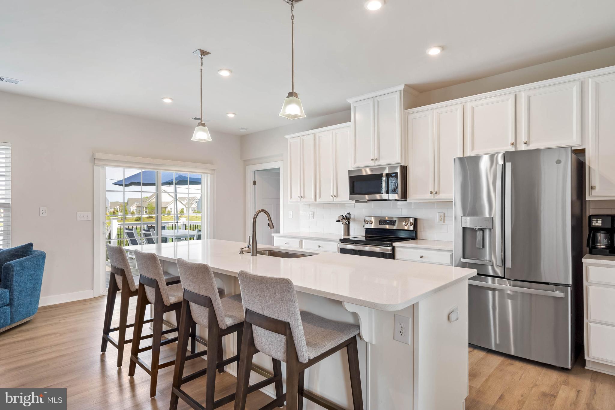 19016 Trimaran Drive Lewes, DE 19958 - Photo 11 of 44 a kitchen with stainless steel appliances a dining table chairs microwave and refrigerator