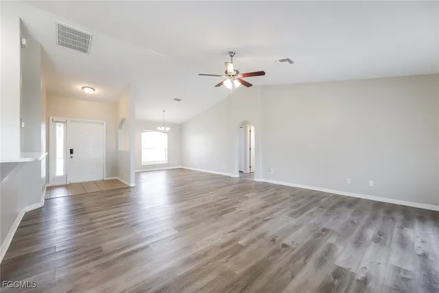 a view of an empty room with a window and wooden floor
