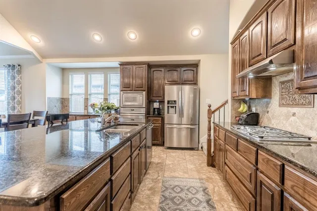 a large kitchen with stainless steel appliances granite countertop a lot of counter space and refrigerator