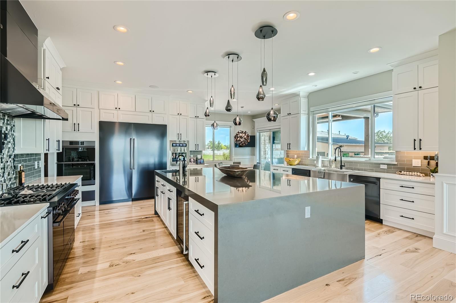 1757 Whistlepig Lane Broomfield, CO 80020 - Photo 26 of 50 a large kitchen with stainless steel appliances kitchen island granite countertop a large counter top a stove a chimney a sink and a refrigerator