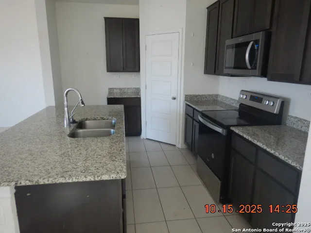 a kitchen with granite countertop a stove a sink and a microwave