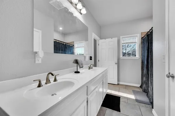 a spacious bathroom with a double vanity sink a mirror and a shower