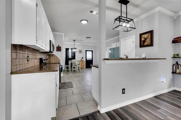 a view of a kitchen with stainless steel appliances granite countertop a refrigerator a oven a stove and a sink with wooden floor
