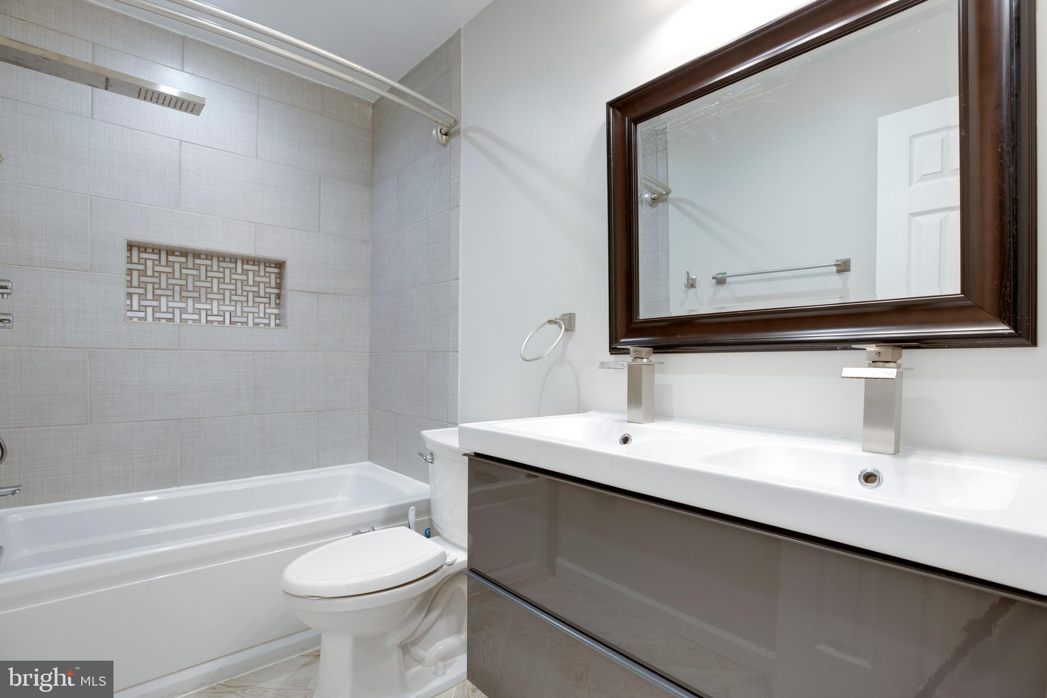 9513 Burdett Road Burke, VA 22015 - Photo 17 of 40 a bathroom with a toilet a sink a mirror and a bathtub