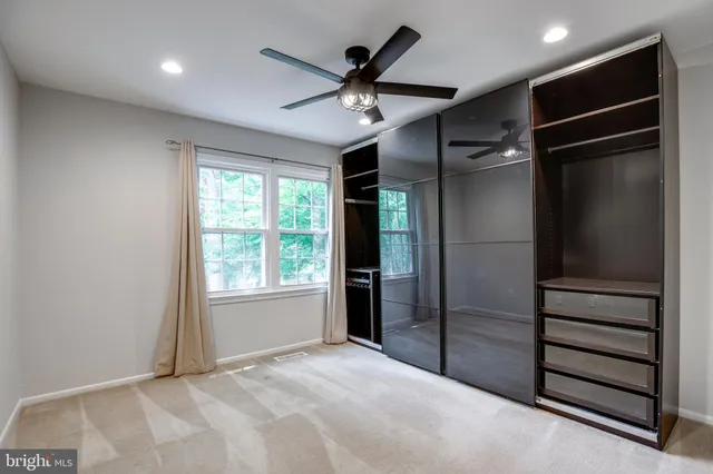 an empty room with windows and ceiling fan