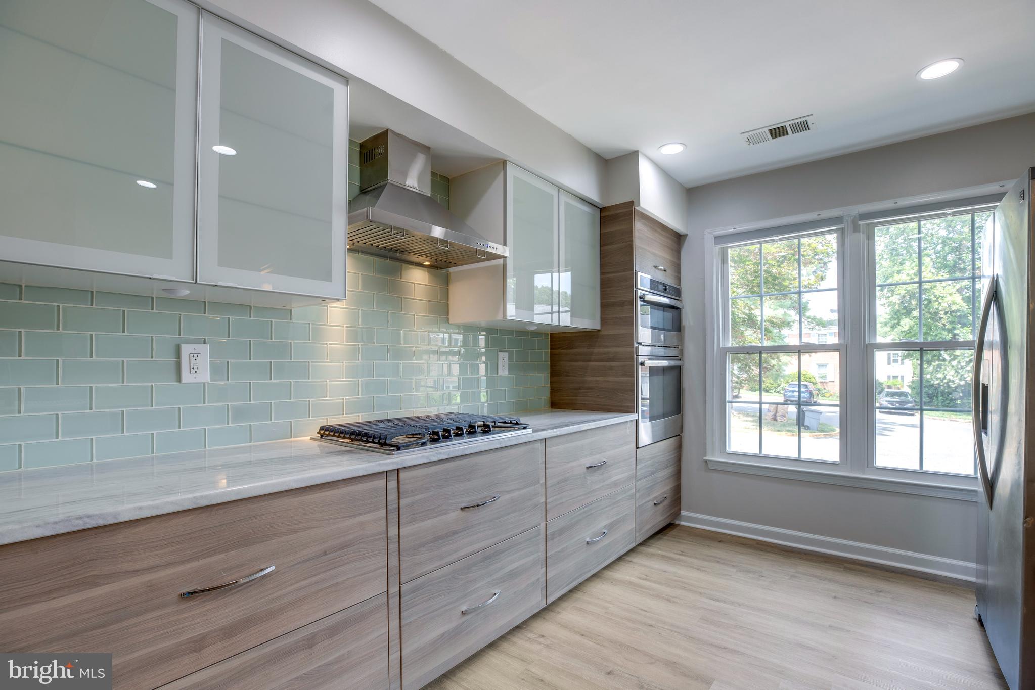9513 Burdett Road Burke, VA 22015 - Photo 10 of 40 a kitchen with stainless steel appliances kitchen island granite countertop a stove a sink and white cabinets