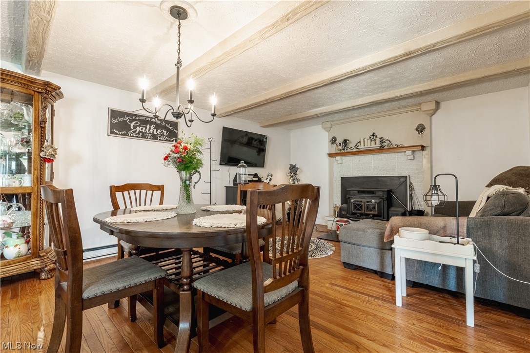 10450 Gavers Road Hanoverton, OH 44423 - Photo 13 of 50 Dining room with a brick fireplace, beam ceiling, light hardwood / wood-style flooring, a textured ceiling, and a chandelier