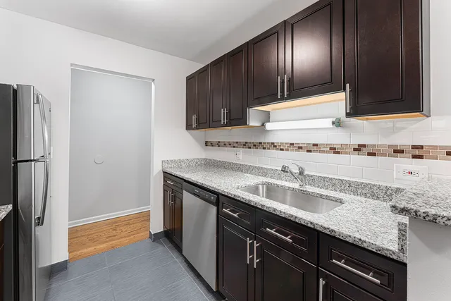 a kitchen with granite countertop stainless steel appliances a sink and a refrigerator