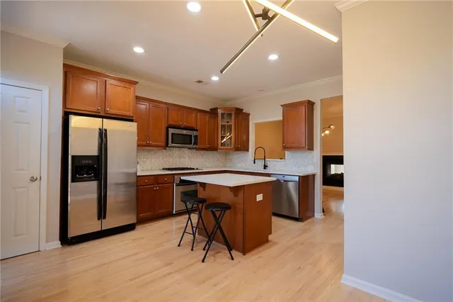 a kitchen with stainless steel appliances granite countertop a refrigerator a sink dishwasher a stove with wooden cabinets and floor