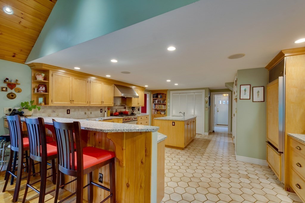 29 Sheridan Road Wellesley, MA 02481 - Photo 12 of 32 a kitchen with stainless steel appliances kitchen island granite countertop dining table chairs and a refrigerator