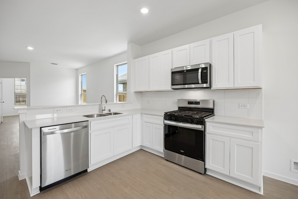 15023 Rustic Moon Road Conroe, TX 77302 - Photo 10 of 32 a kitchen with white cabinets and stainless steel appliances