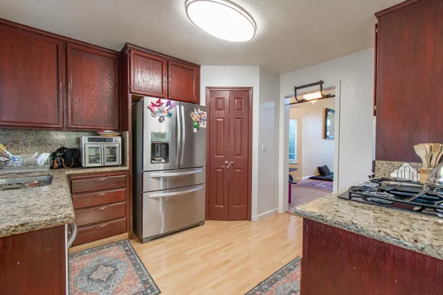 a kitchen with stainless steel appliances kitchen island granite countertop a refrigerator and a sink