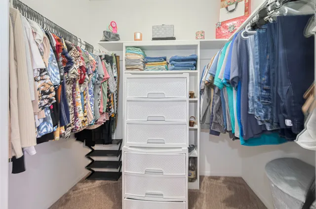 a view of walk in closet with clothes and shoes