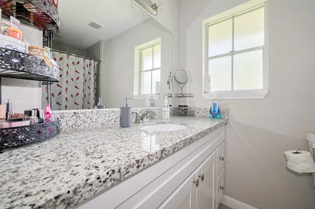 a bathroom with a granite countertop sink and a window