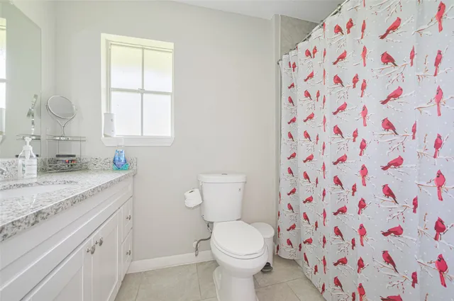 a bathroom with a granite countertop sink a toilet and a shower curtain