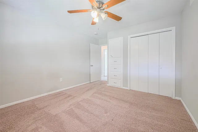 an empty room with closet and a chandelier fan